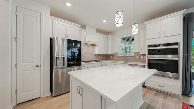 314 Red Barn Rd, Saint Augustine, FL 32092 - kitchen featuring light wood finished floors, stainless steel appliances, a kitchen island, a sink, and wall chimney range hood