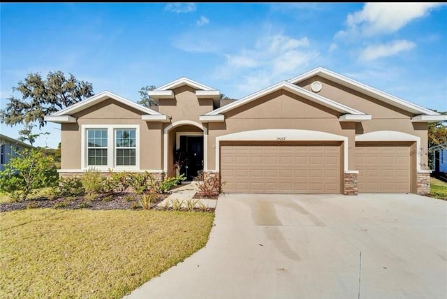 view of front of house featuring stucco siding, stone siding, driveway, a front lawn, and a garage