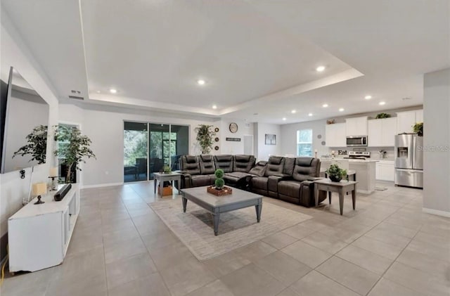 living area with recessed lighting, light tile patterned floors, and a raised ceiling