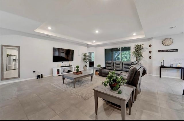 living area featuring a raised ceiling, light tile patterned floors, baseboards, visible vents, and recessed lighting