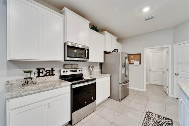kitchen featuring visible vents, appliances with stainless steel finishes, white cabinetry, light stone counters, and light tile patterned floors