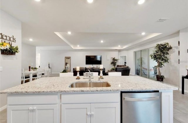 kitchen with stainless steel dishwasher, open floor plan, a sink, and a raised ceiling