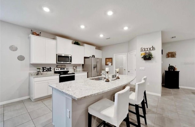 kitchen with a kitchen bar, recessed lighting, a center island with sink, appliances with stainless steel finishes, and a sink