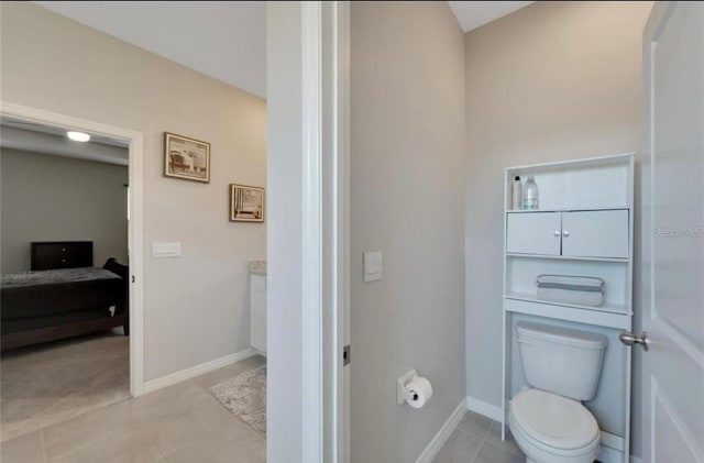 ensuite bathroom featuring ensuite bathroom, baseboards, toilet, and tile patterned floors