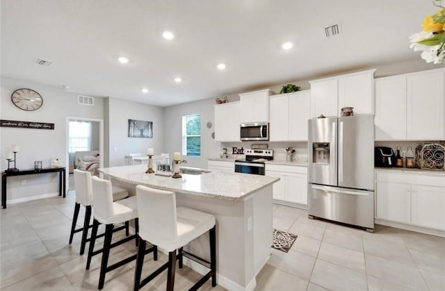 kitchen featuring visible vents, a kitchen island with sink, recessed lighting, appliances with stainless steel finishes, and a breakfast bar area