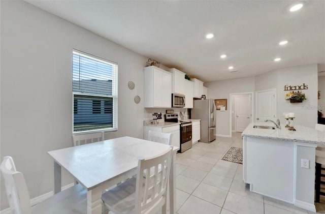 kitchen featuring recessed lighting, stainless steel appliances, a sink, an island with sink, and white cabinets