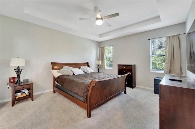bedroom featuring baseboards, light carpet, and a raised ceiling