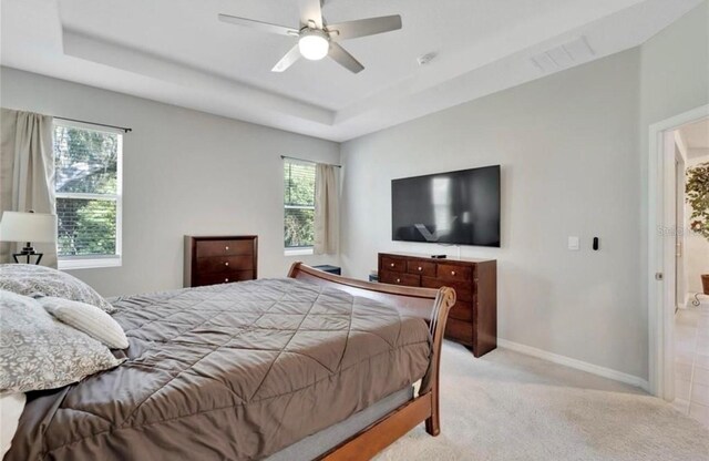 bedroom featuring light carpet, multiple windows, visible vents, and a raised ceiling