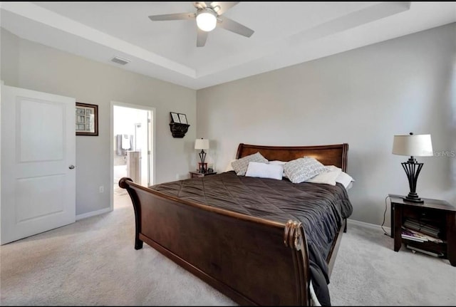 bedroom featuring visible vents, baseboards, a ceiling fan, light carpet, and a tray ceiling