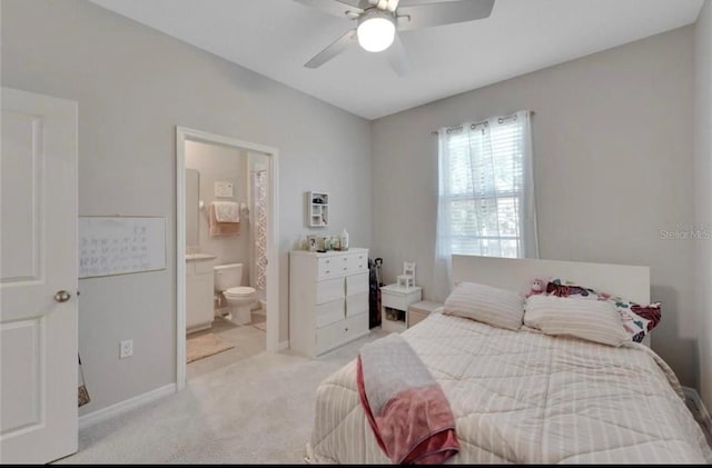 bedroom with baseboards, ensuite bath, ceiling fan, and light colored carpet