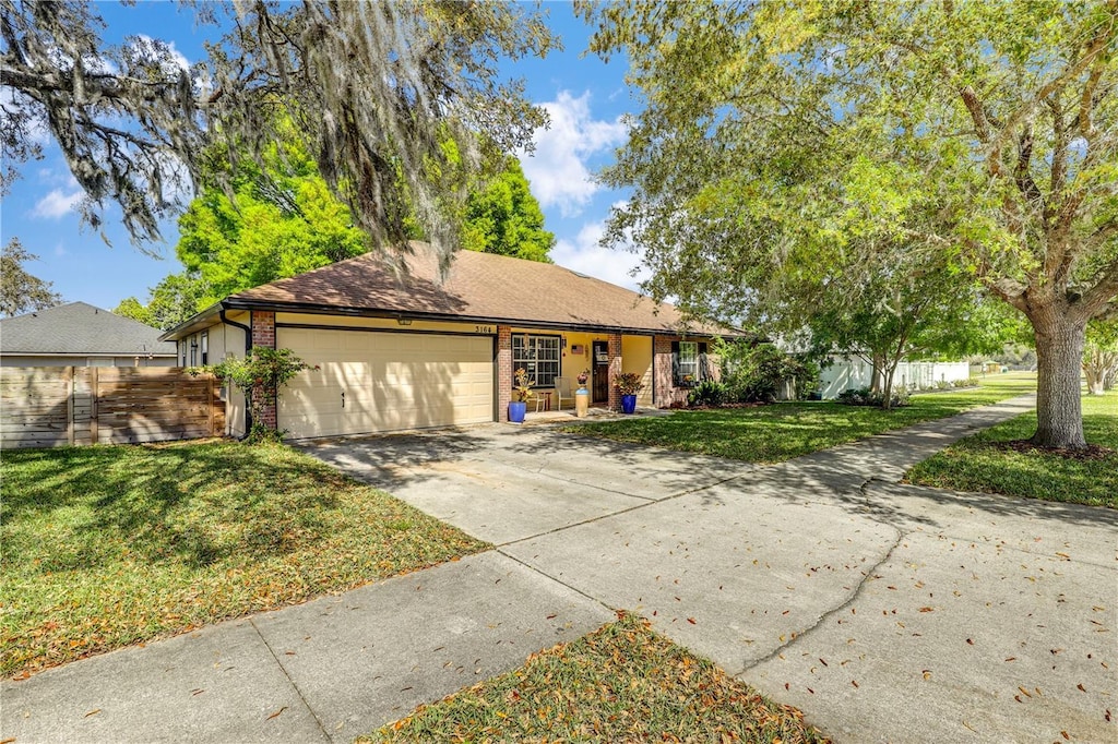 single story home with fence, an attached garage, a front yard, brick siding, and driveway