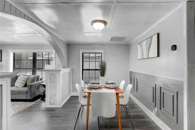 dining room featuring dark wood-type flooring, arched walkways, visible vents, and ornamental molding