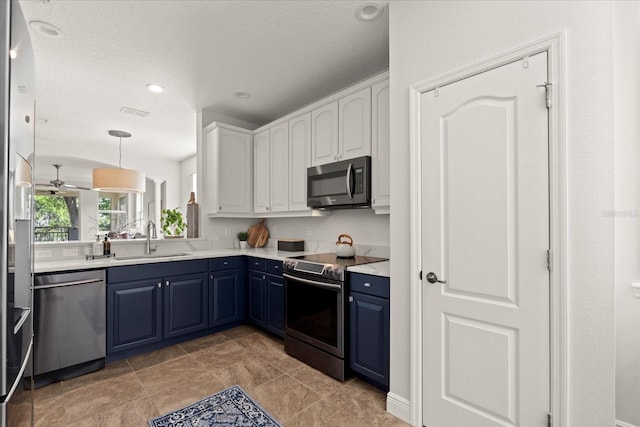 kitchen featuring a sink, white cabinets, light countertops, blue cabinetry, and appliances with stainless steel finishes