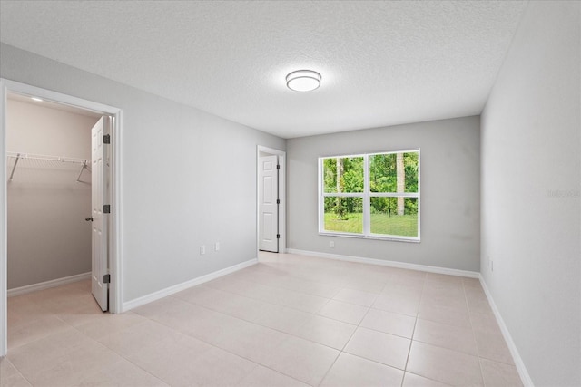 29 Secretary Trl, Palm Coast, FL 32164 - unfurnished bedroom with light tile patterned flooring, a walk in closet, baseboards, and a textured ceiling