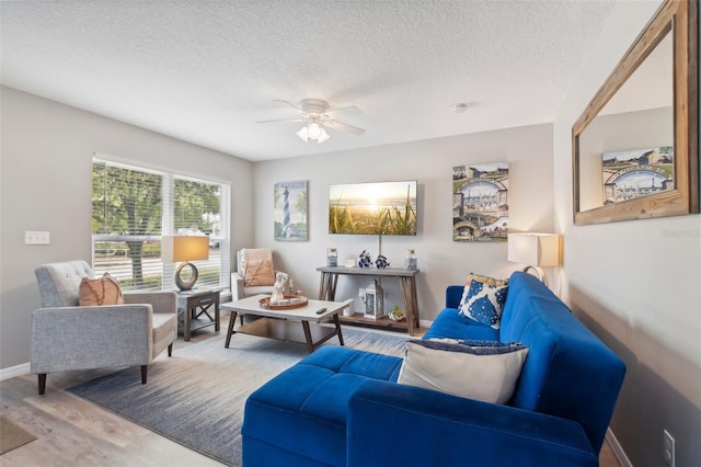 living room with baseboards, a textured ceiling, wood finished floors, and a ceiling fan