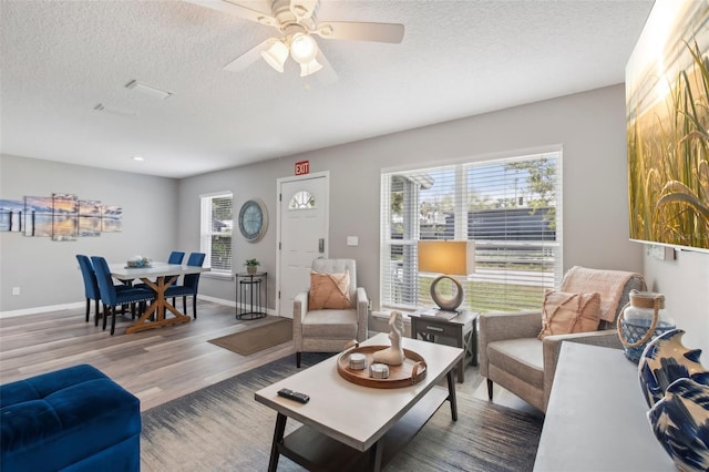 living area featuring a textured ceiling, a healthy amount of sunlight, ceiling fan, and wood finished floors