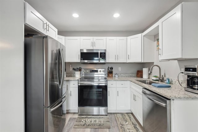 kitchen featuring white cabinets, a sink, light wood-style floors, and appliances with stainless steel finishes