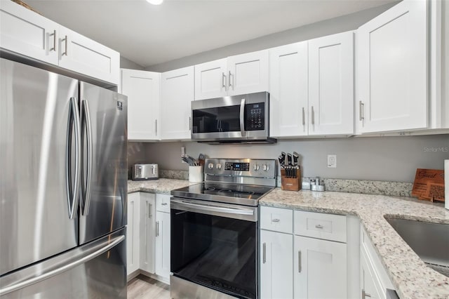 kitchen with light wood finished floors, white cabinetry, light stone countertops, and stainless steel appliances
