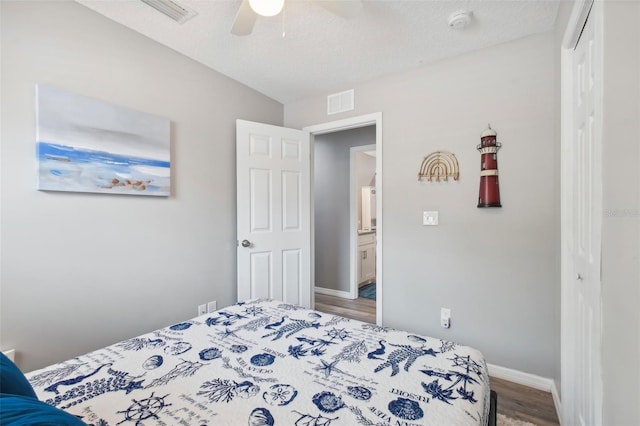 bedroom with wood finished floors, baseboards, a closet, and visible vents