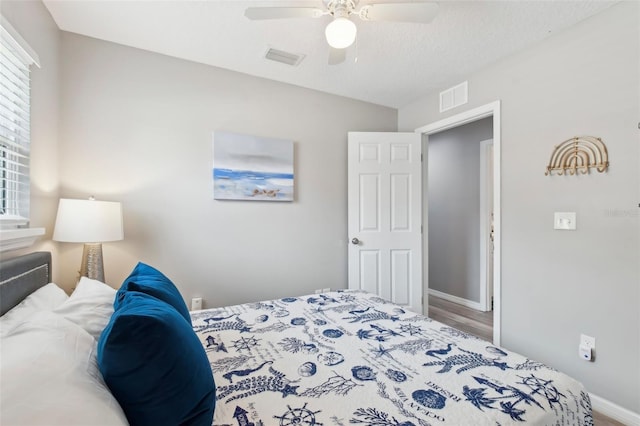 bedroom with baseboards, visible vents, a ceiling fan, and wood finished floors