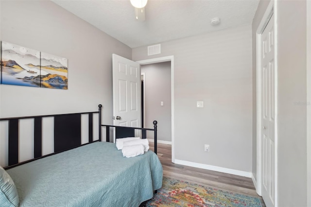 bedroom featuring baseboards, visible vents, a closet, and wood finished floors