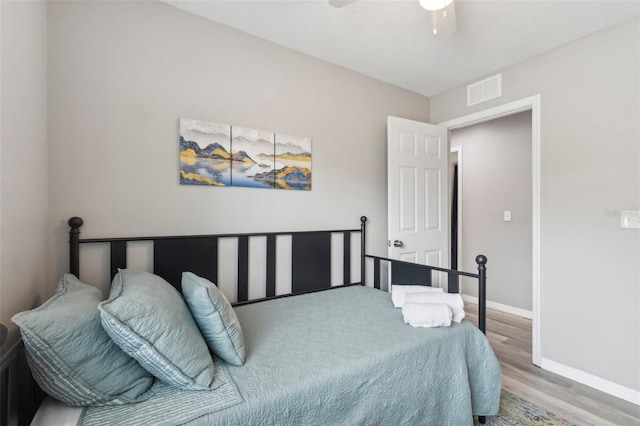 bedroom featuring a ceiling fan, wood finished floors, baseboards, and visible vents