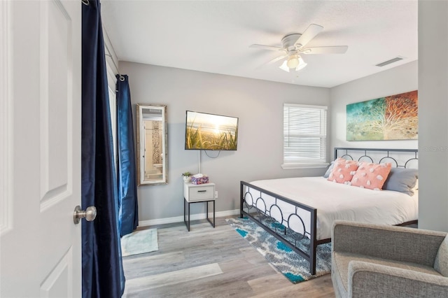 bedroom featuring baseboards, visible vents, wood finished floors, and a ceiling fan