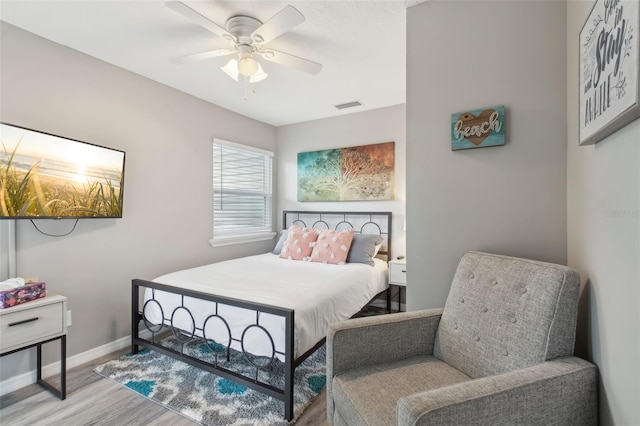 bedroom with baseboards, visible vents, a ceiling fan, and wood finished floors