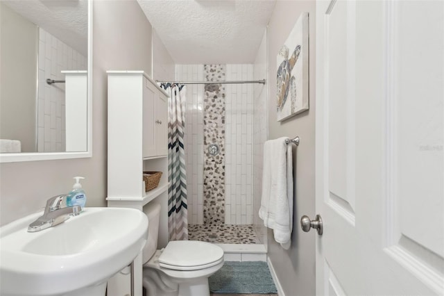 bathroom featuring a stall shower, toilet, a sink, and a textured ceiling