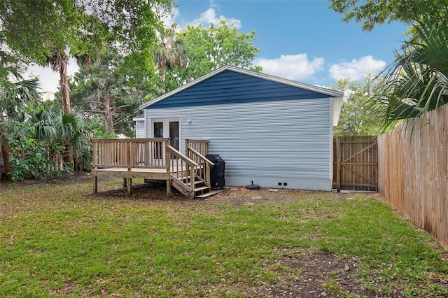 rear view of property with a lawn, fence, a wooden deck, and crawl space