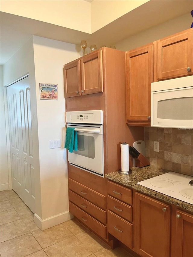 102 Yacht Harbor Dr Unit 375, Palm Coast, FL 32137 - kitchen with backsplash, light tile patterned floors, white appliances, baseboards, and dark stone counters