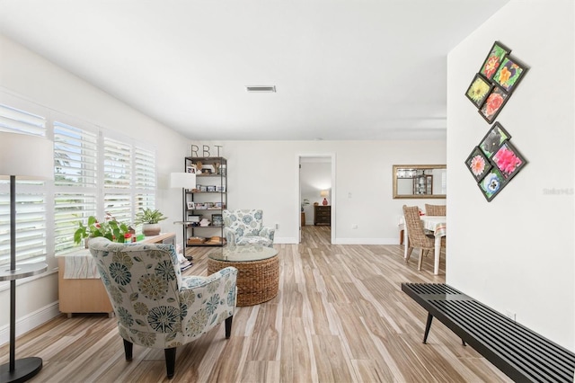 sitting room featuring baseboards, light wood-style floors, and visible vents