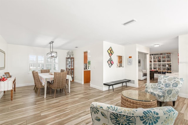 living room featuring plenty of natural light, baseboards, light wood finished floors, and visible vents