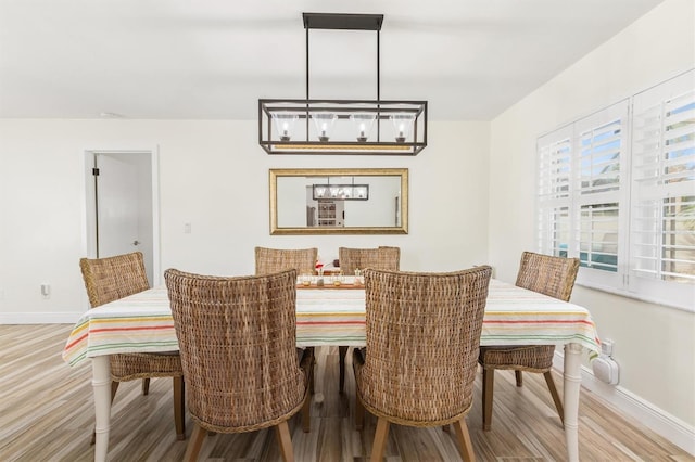 dining area featuring baseboards, wood finished floors, and a chandelier