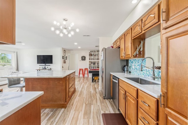 kitchen featuring light wood-type flooring, a chandelier, a sink, visible vents, and dishwasher