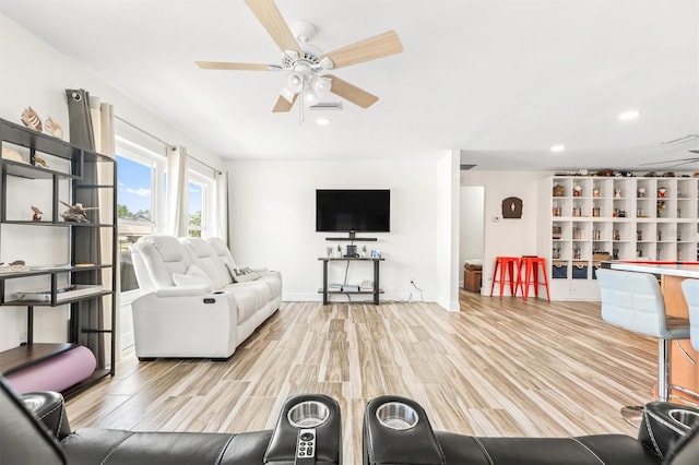 living area with baseboards, a ceiling fan, and light wood finished floors
