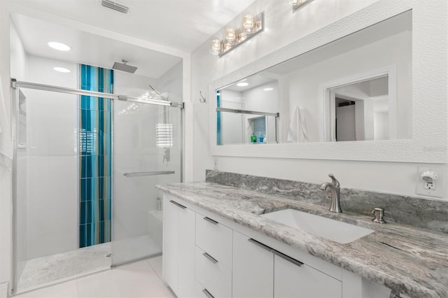 bathroom with tile patterned floors, vanity, a stall shower, and visible vents