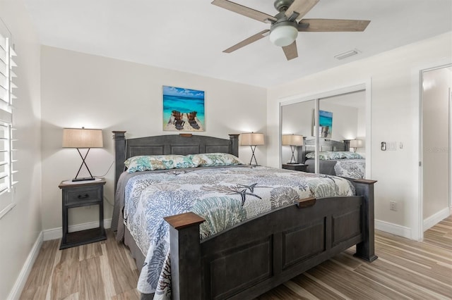 bedroom with baseboards, visible vents, a closet, and wood finished floors