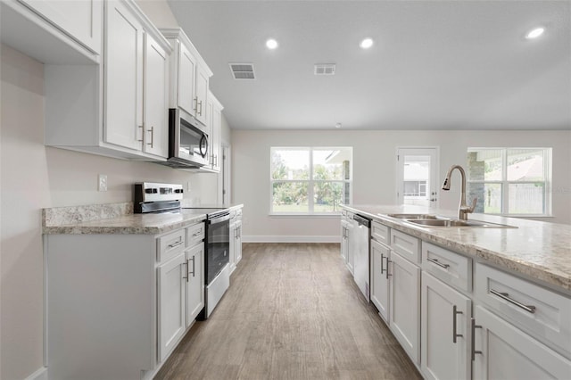12 Squanto Pl, Palm Coast, FL 32164 - kitchen with stainless steel appliances, a sink, light wood-type flooring, white cabinets, and baseboards