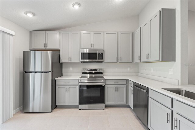 31 Secretary Trl, Palm Coast, FL 32164 - kitchen with light countertops, lofted ceiling, gray cabinets, light tile patterned floors, and stainless steel appliances