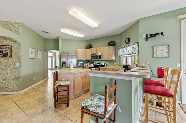 42 Buffalo Bill Dr, Palm Coast, FL 32137 - kitchen featuring visible vents, light tile patterned floors, a kitchen bar, light brown cabinetry, and stainless steel appliances