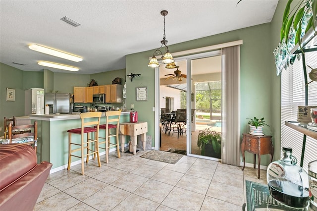42 Buffalo Bill Dr, Palm Coast, FL 32137 - kitchen with light tile patterned floors, a peninsula, visible vents, a breakfast bar, and appliances with stainless steel finishes