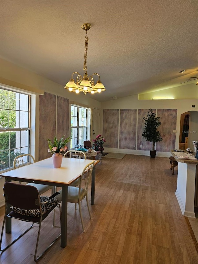8 Rickenbacker Dr, Palm Coast, FL 32164 - dining room with a chandelier, arched walkways, a textured ceiling, and light wood-style flooring