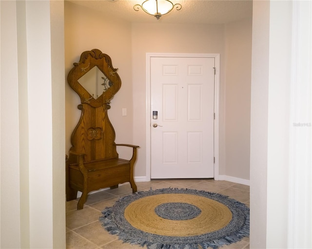 tiled foyer entrance with a textured ceiling and baseboards