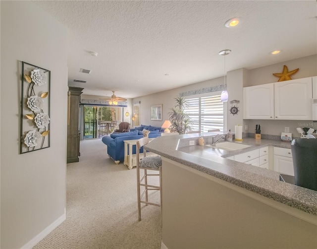 kitchen featuring a sink, white cabinets, plenty of natural light, and a textured ceiling