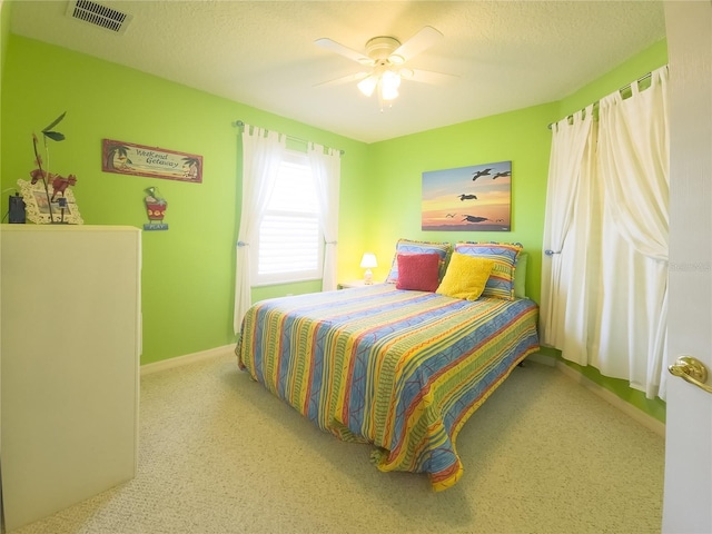 carpeted bedroom featuring visible vents, baseboards, a ceiling fan, and a textured ceiling