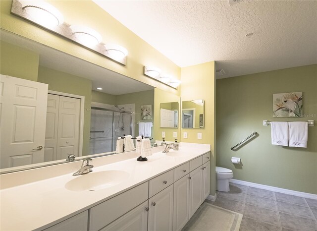 bathroom with toilet, a stall shower, double vanity, and a sink