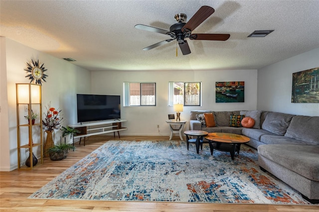living room featuring wood finished floors, a ceiling fan, and visible vents