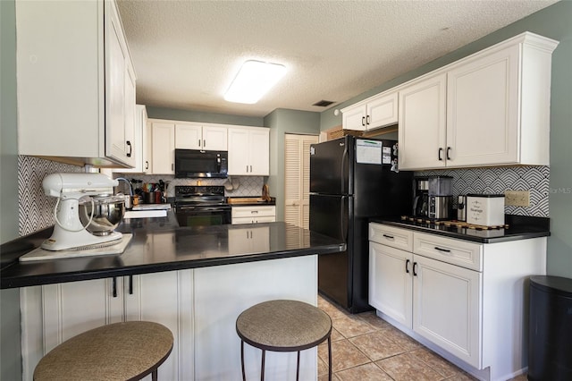 kitchen with a peninsula, dark countertops, white cabinets, black appliances, and a sink