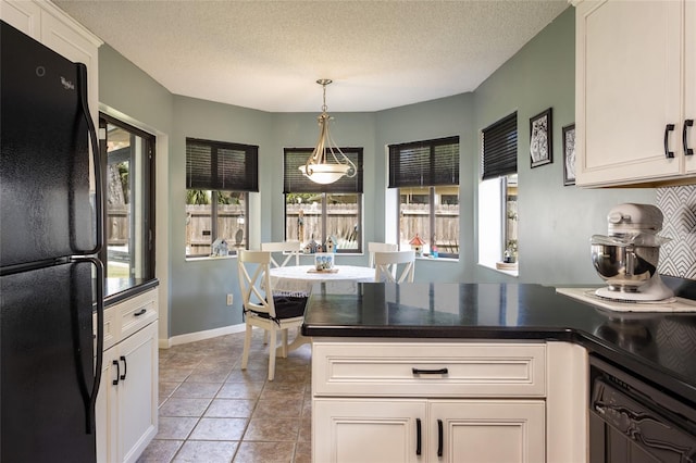 kitchen with dark countertops, freestanding refrigerator, a peninsula, a textured ceiling, and pendant lighting